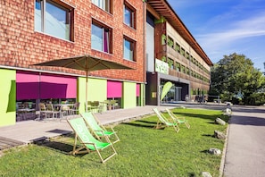 Un hotel con terraza al aire libre y zona verde.