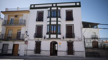 Un edificio de varios pisos con una entrada central, balcones y fachada a cuadros.