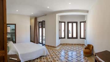 A bedroom with a bed, a chair, a table, and a window with a view.