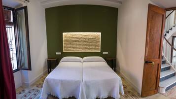 A room with a bed, a window with a textured wall, a staircase, and a door.