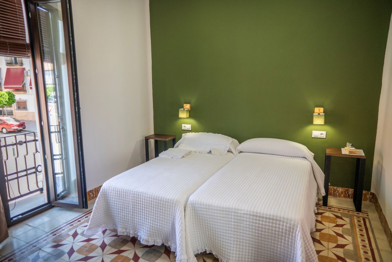 A room with two beds, a green wall, and a patterned floor.