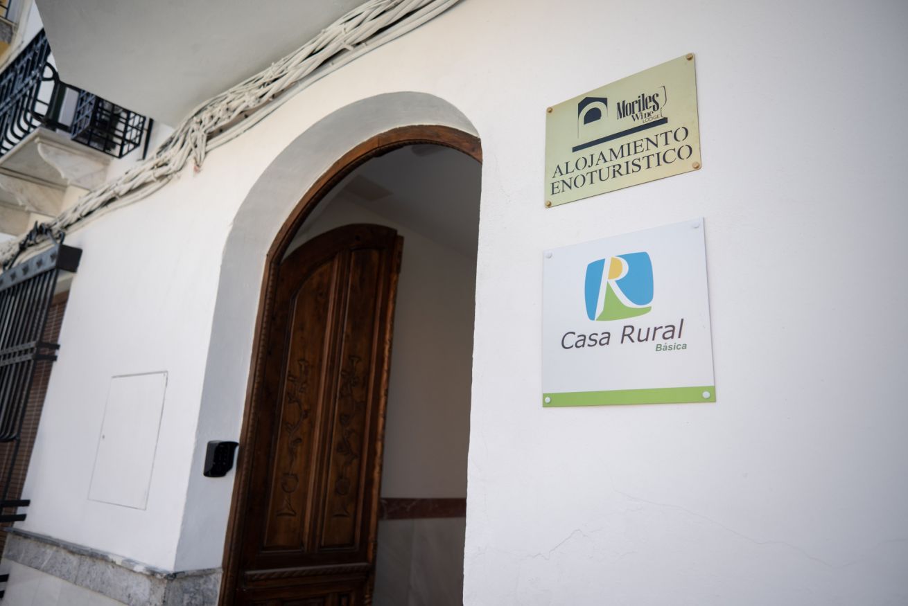L'ingresso di un edificio con una porta in legno e un cartello che indica 'Alojamiento Enoturistico' e 'Casa Rural Básica'.