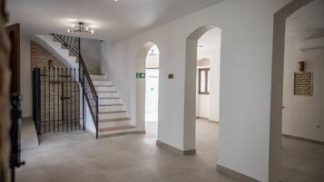A spacious interior with a staircase, white walls, and a stone accent wall.