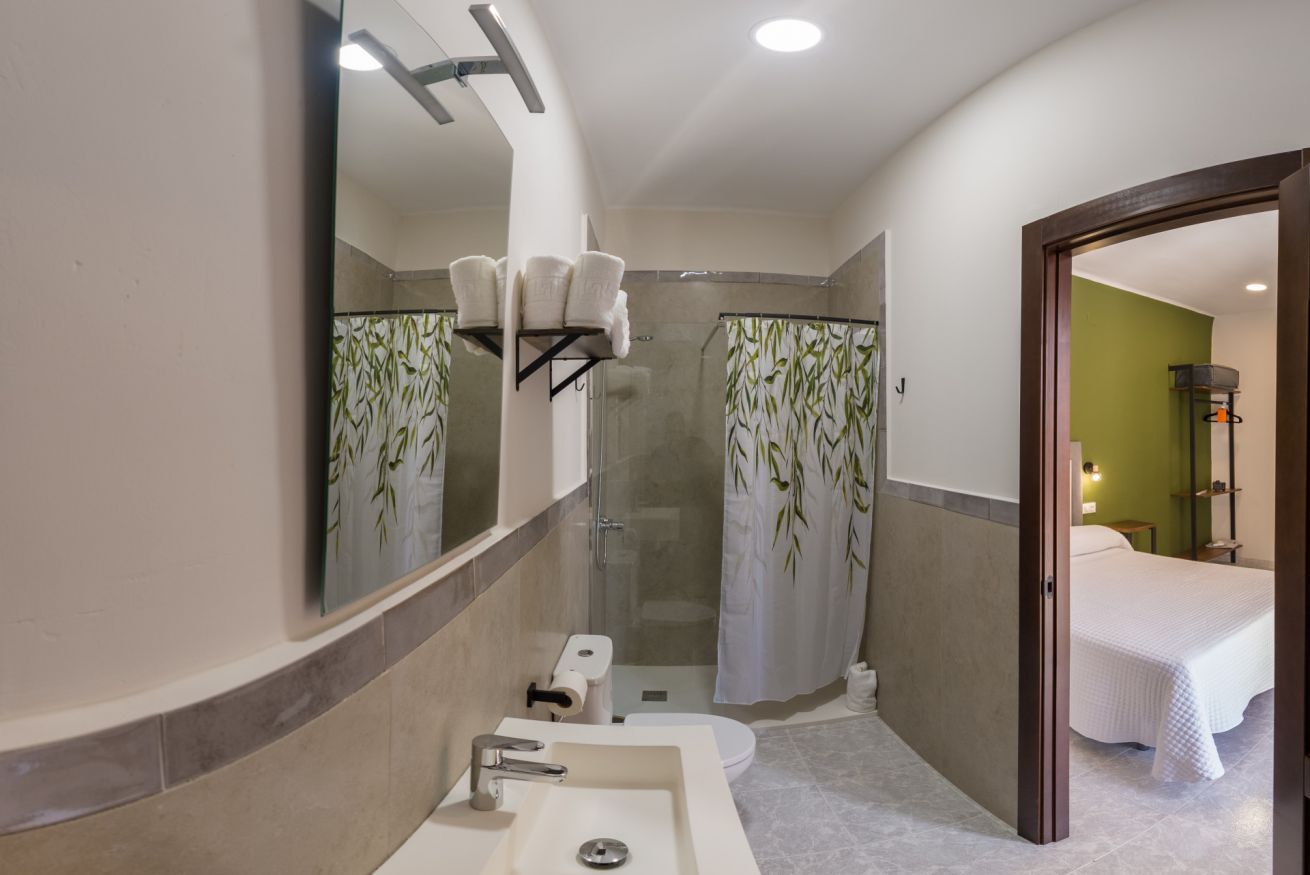 Ein modernes Badezimmer mit großem Spiegel, zwei Waschbecken, einer Dusche und einer Toilette.