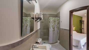 A modern bathroom with a large mirror, two sinks, a shower, and a toilet.