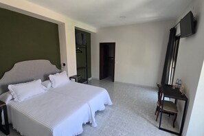 A hotel room with a large bed, a desk, a chair, and a TV.