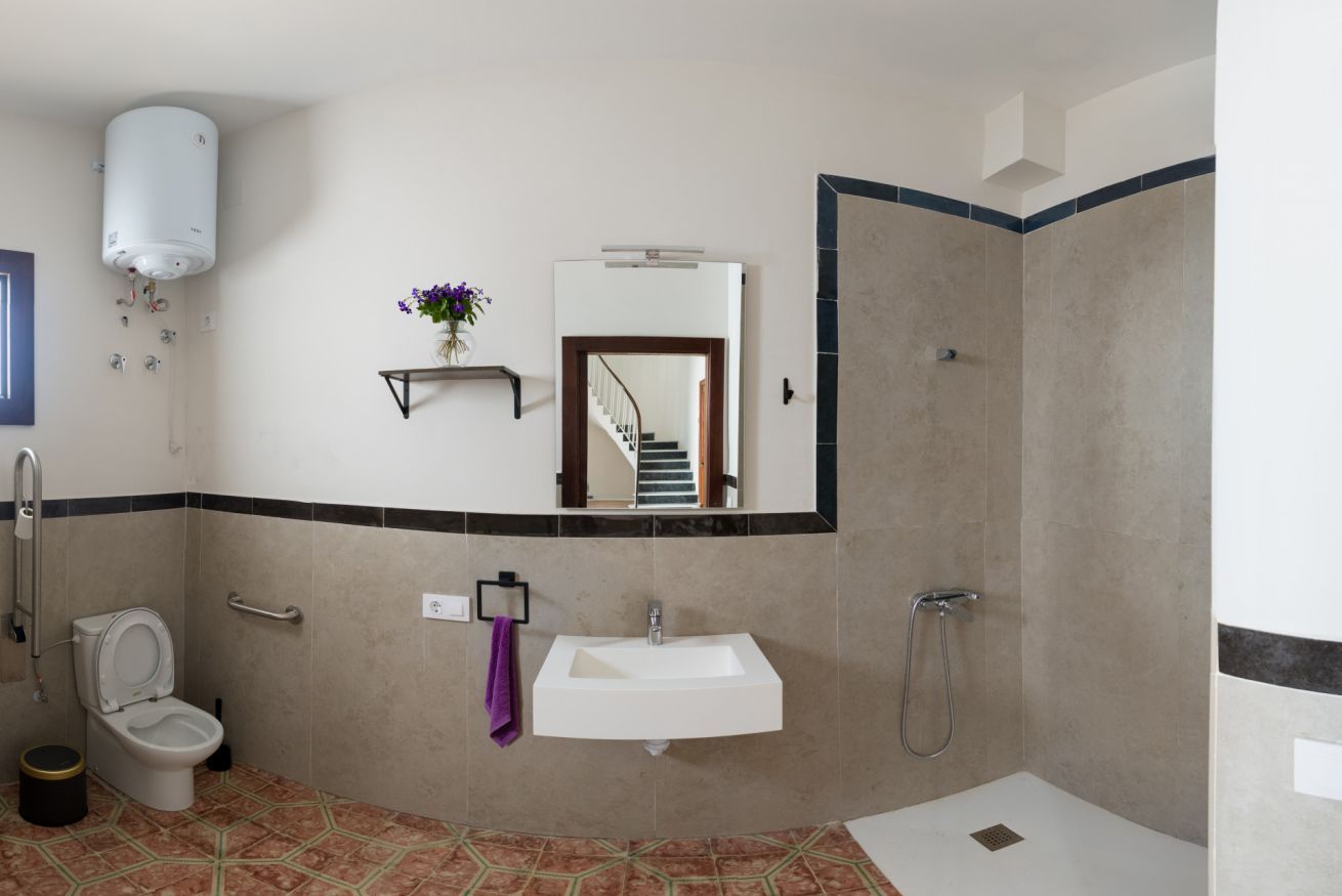A bathroom with a toilet, sink, shower, and a mirror.