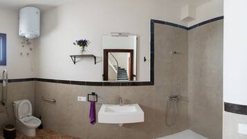 A bathroom with a toilet, sink, shower, and a mirror.