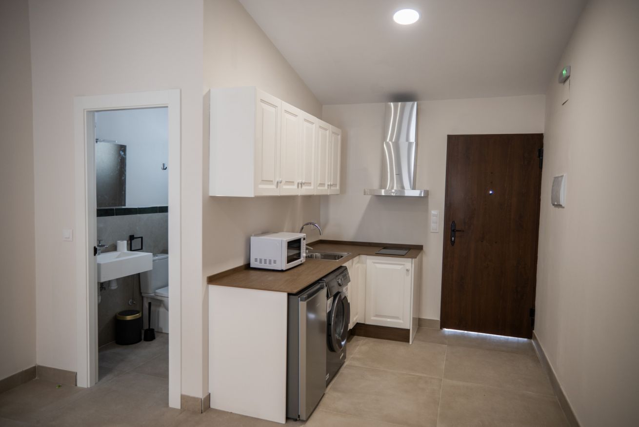 Cocina compacta con lavadora, microondas y pileta.