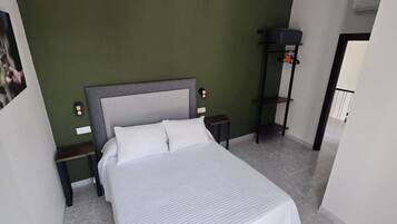 A bedroom with a bed, nightstands, a wall-mounted shelf, and a door.