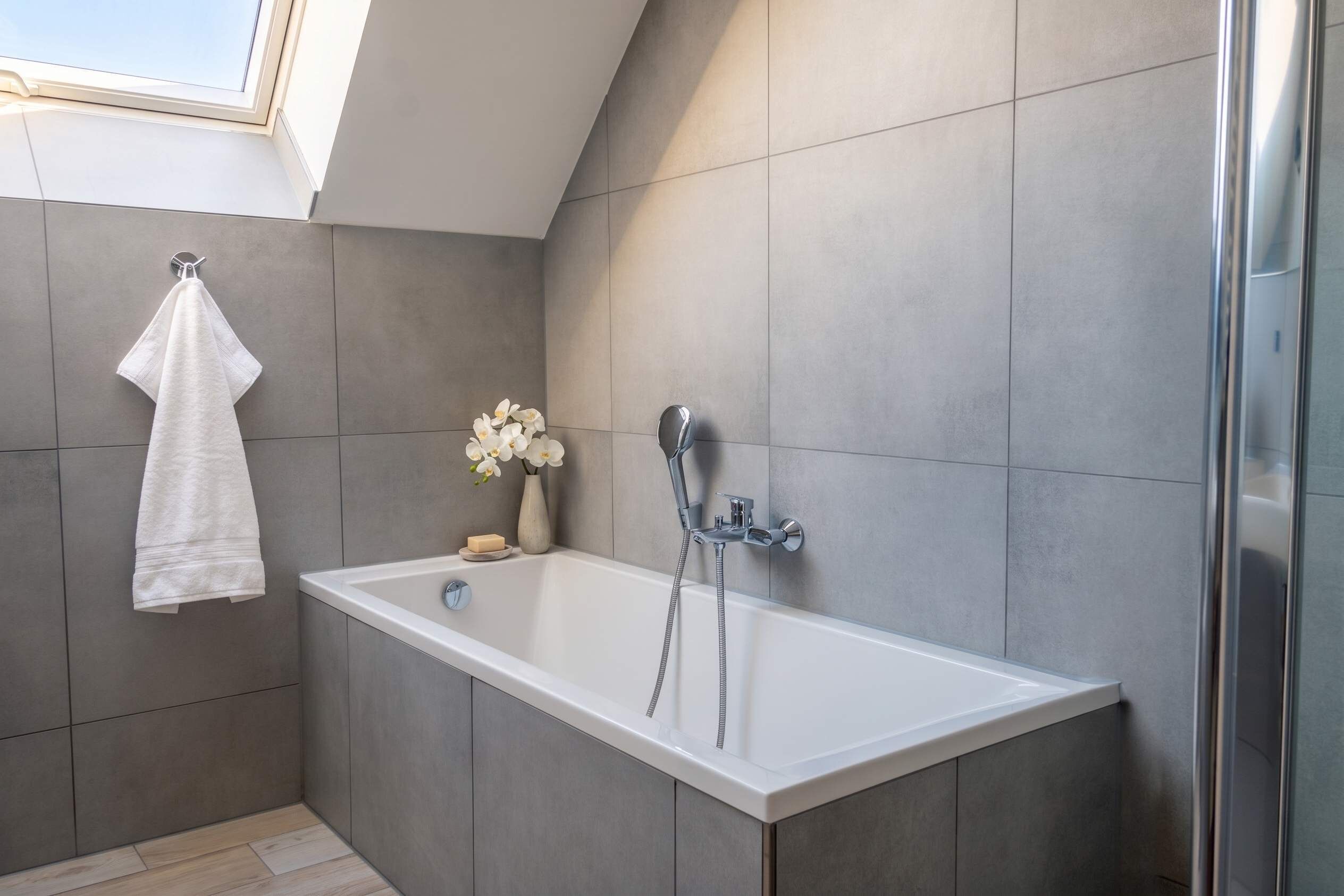Un baño moderno con bañera, ducha y tragaluz.