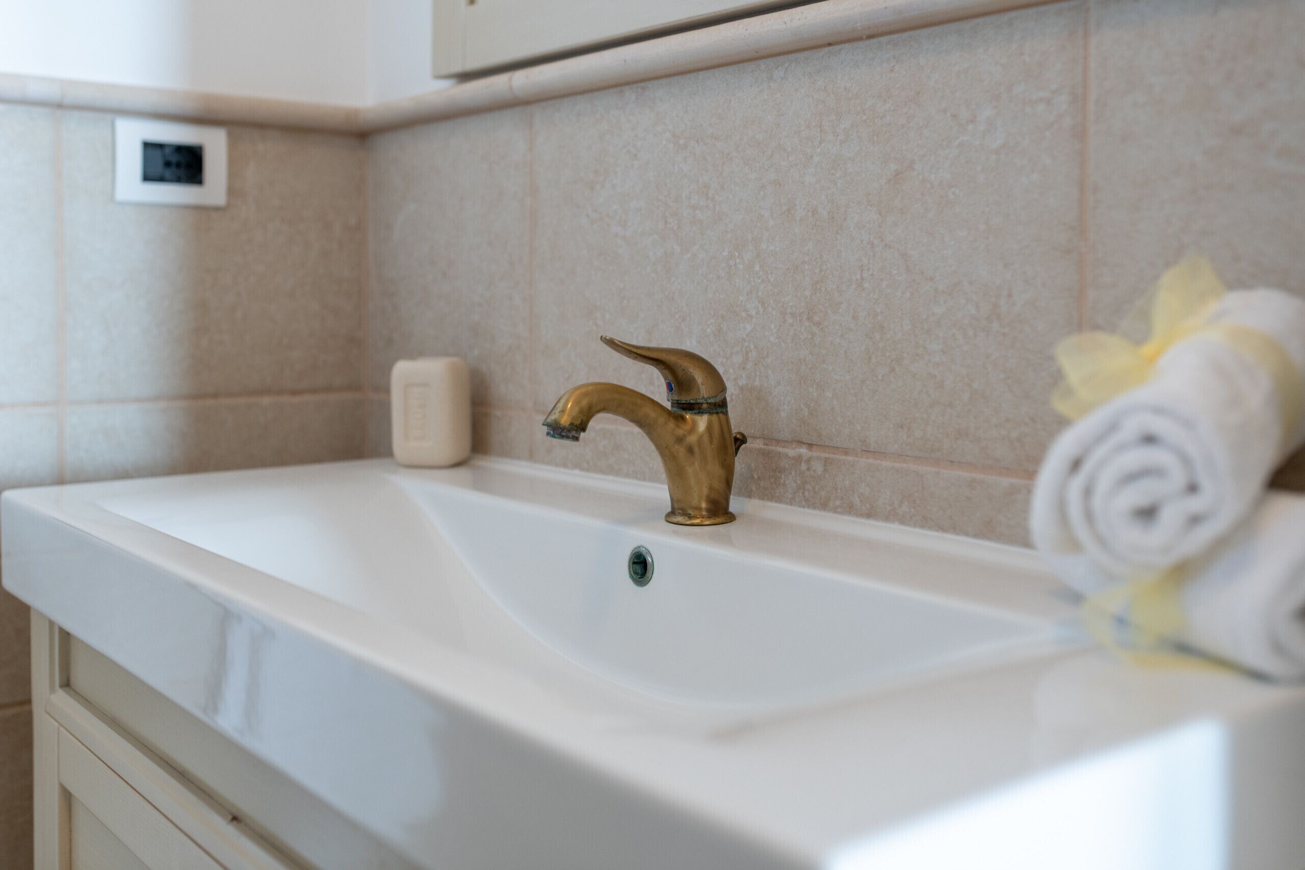 A bathroom with a white sink, a gold faucet, and a towel on the right.