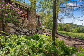 Ein Steinhaus mit einer Veranda, umgeben von üppigem Grün und Farne.