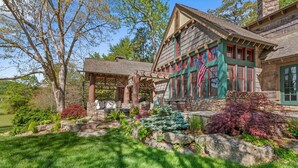 A traditional stone house with a covered patio, a stone fireplace, and a well-maintained garden. - Farm Hollow - luxury home with hot tub, covered fireplace (Banner Elk)