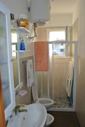 A bathroom with a toilet, sink, and shower enclosure. - Comfortable Vacation Retreat in a Central Area (San Michele al Tagliamento)