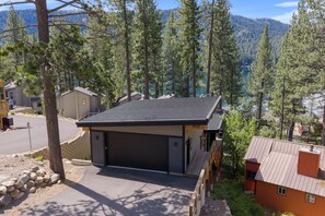 Eine Hütte mit Garage, umgeben von Bäumen und Blick auf einen Berg.