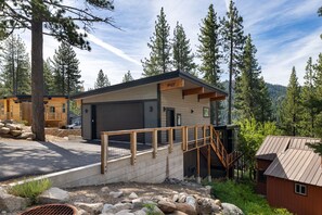 Eine moderne Holzhütte mit einer Holzterrasse, einer Treppe und Blick auf den umliegenden Wald.