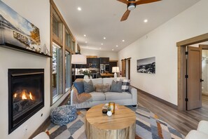 Ein geräumiges Wohnzimmer mit Kamin, einer Couch, einem Couchtisch und einem Essbereich im Hintergrund.