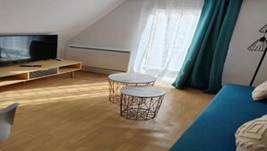 A small, modern room with a TV, two round tables, a sofa, and a window with curtains. - 200 m plage - Rue piétonne à 300 m - jardin (Berck)
