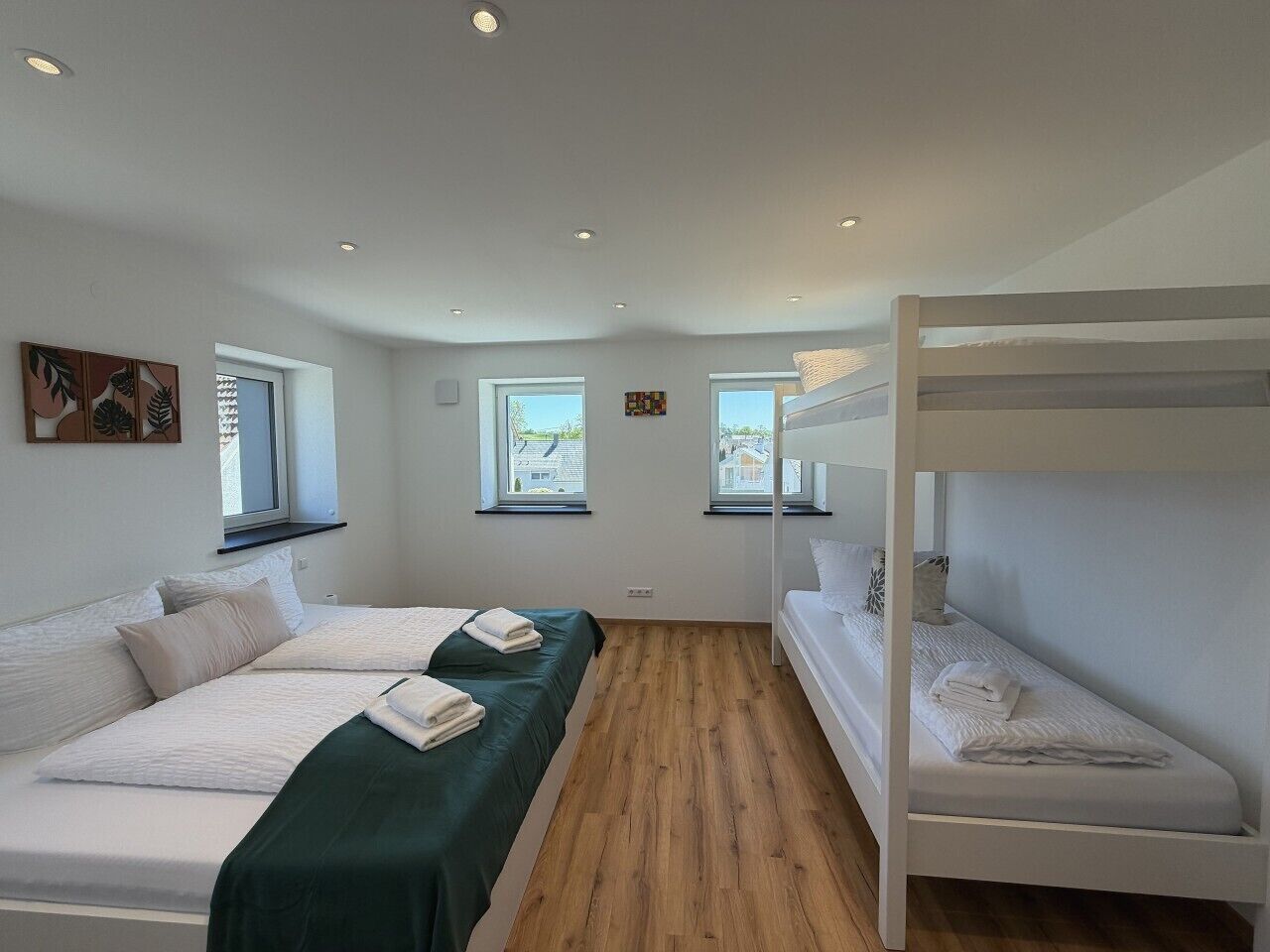 Ein Schlafzimmer mit zwei Betten, einem Etagenbett, Holzboden und Fenstern mit Aussicht.