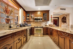 A kitchen with wooden cabinets, stainless steel appliances, and a granite countertop. - PREMIUM OCEAN VIEW Remodeled Third Floor at Villa La Estancia Beachfront Resort (Cabo San Lucas)