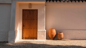 Une entrée d’immeuble avec une porte en bois, un mur blanc et un toit recouvert de tuiles.