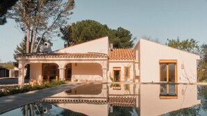 Une maison moderne avec un toit en tuiles, une piscine et son reflet dans l’eau.