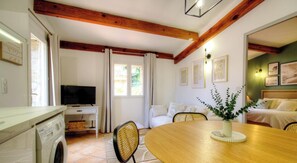 Une pièce comprenant une table à manger en bois, un téléviseur, un lave-linge et un lit avec un mur vert.