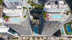 A high-rise building with a rooftop pool, a tennis court, and a landscaped area with palm trees. - Brickell Heights High-Floor Suite with King Bed, Den, 2 Baths, Skyline Views (Miami)