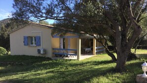 A small, single-story building with a porch and a table. - Casetta des Oliviers (SARTENE)