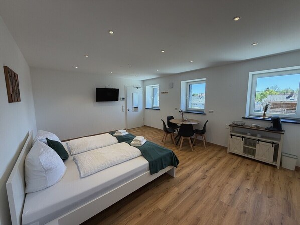 Una habitación moderna con cama, escritorio y kitchenette.