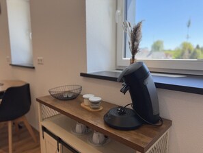 Una encimera de cocina con una cafetera, un bol y dos recipientes.