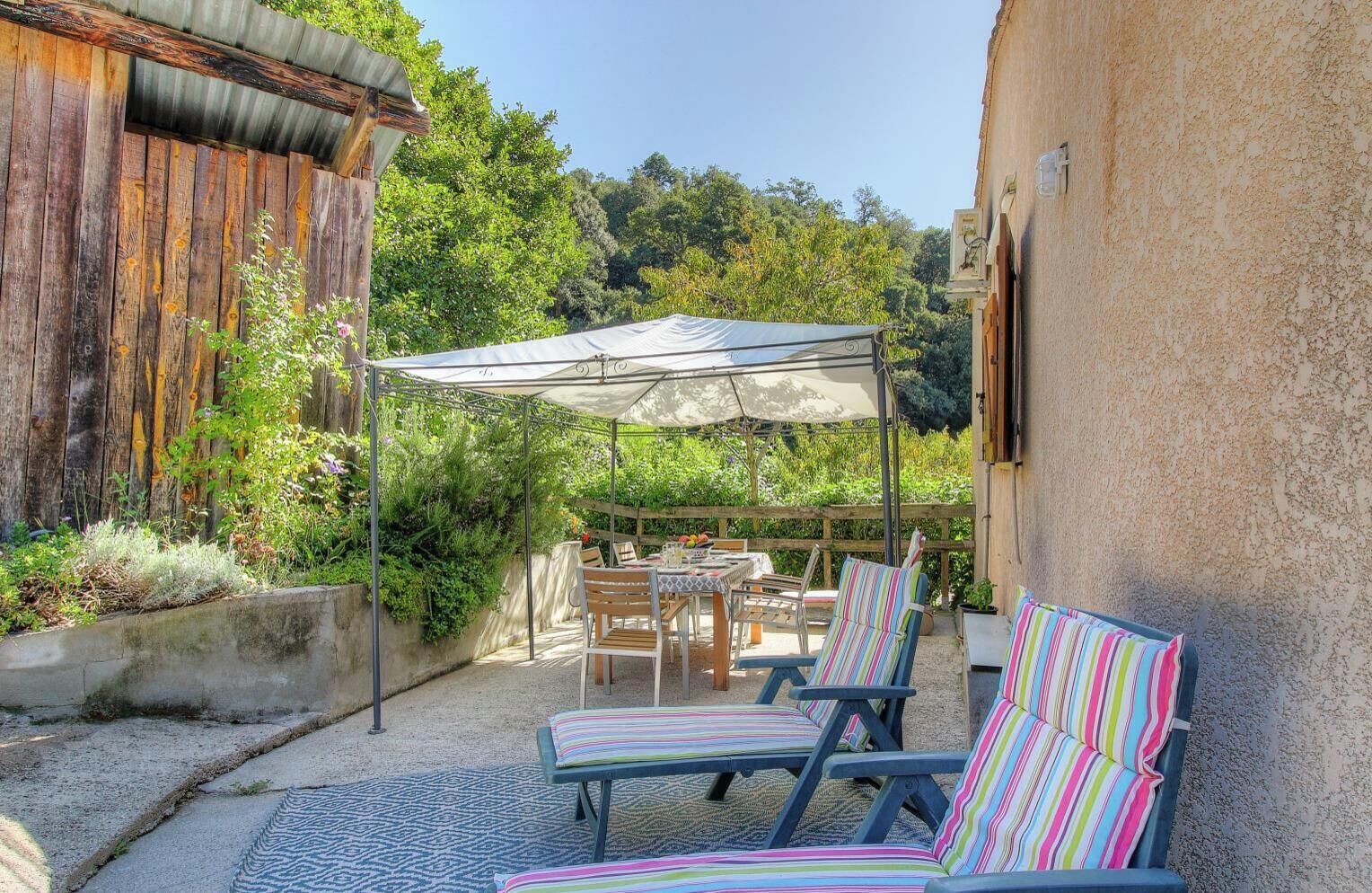 A patio with a table and chairs, a striped cushion, and a canopy.