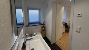 Un bagno moderno con un lavandino grande, una finestra e vista su una sala da pranzo.