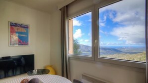 Ein Zimmer mit einem Bett, einem Bild an der Wand, einem Fenster mit Blick auf die Landschaft und einer Heizung.