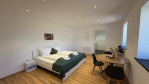 Un dormitorio con cama, mesita de noche y un escritorio pequeño con silla.