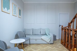 Ett vardagsrum med en soffa, ett litet bord, en stol och en trappa.