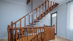 A wooden staircase with a handrail, a door with a window, and a herringbone-patterned floor.