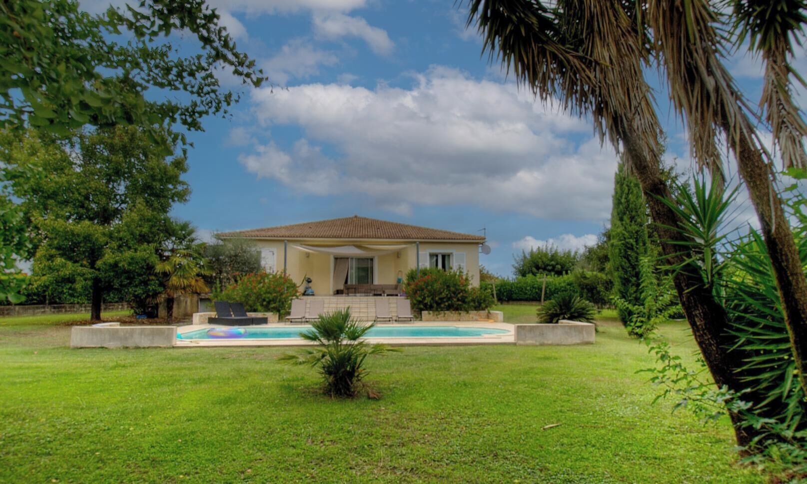 A house with a swimming pool, surrounded by greenery and trees.