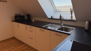 Una cocina con tragaluz, un lavamanos, un microondas y armarios.