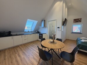A modern kitchen with a dining area, a bed, and a view of the outside.