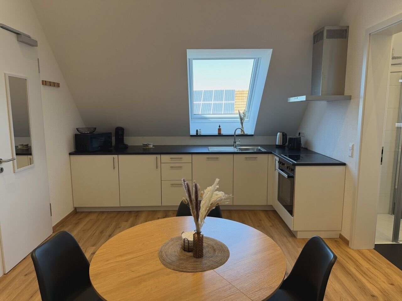 Una cocina moderna con tragaluces, un comedor con mesa redonda y vistas a la ciudad desde la ventana.