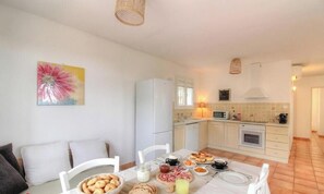 Eine moderne Küche mit weißen Geräten, einem gedeckten Esstisch und einem Bild an der Wand.