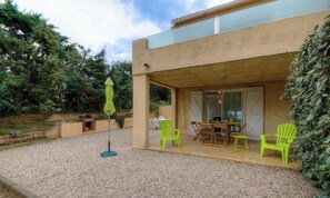 A modern building with a covered patio area, outdoor seating, and a gravel ground. - Vignola - CORBARA - Gîte (CORBARA)