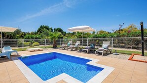 Una piscina rectangular amb un videtell daurat, envoltada per una tanca blanca.