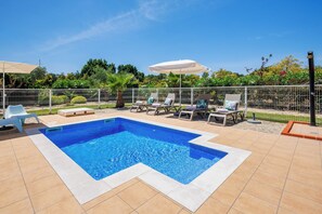Ein rechteckiger Pool mit einer gefliesten Kante, umgeben von einem weißen Zaun.