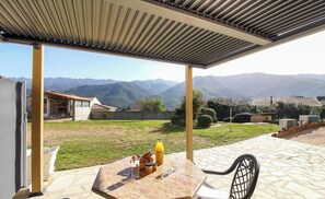 A covered outdoor patio with a stone table, a bottle of orange juice, and a glass. - Petra rossa - PERI - Guest house (PERI)