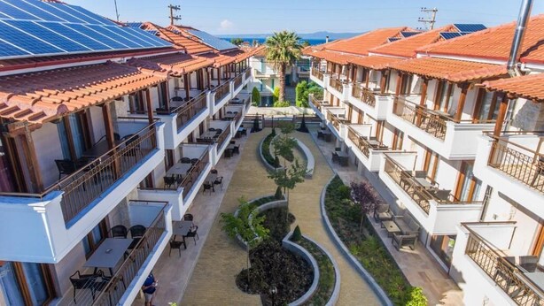 A hotel with multiple floors, outdoor seating areas, and solar panels on the roof.