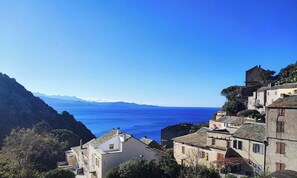 Un village côtier doté d’une architecture traditionnelle, offrant une vue dégagée sur la mer et s’étendant au pied de montagnes.