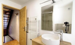 Une salle de bain moderne avec un lavabo blanc, un miroir et une douche.